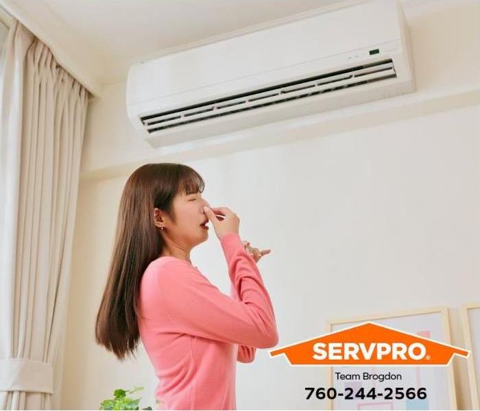 A person notices an unpleasant odor coming from the air conditioner.