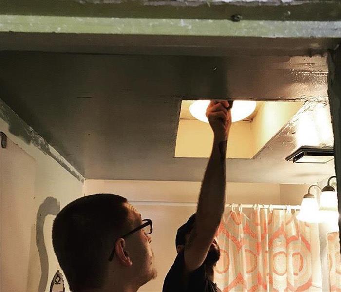 Two male technicians checking ceiling