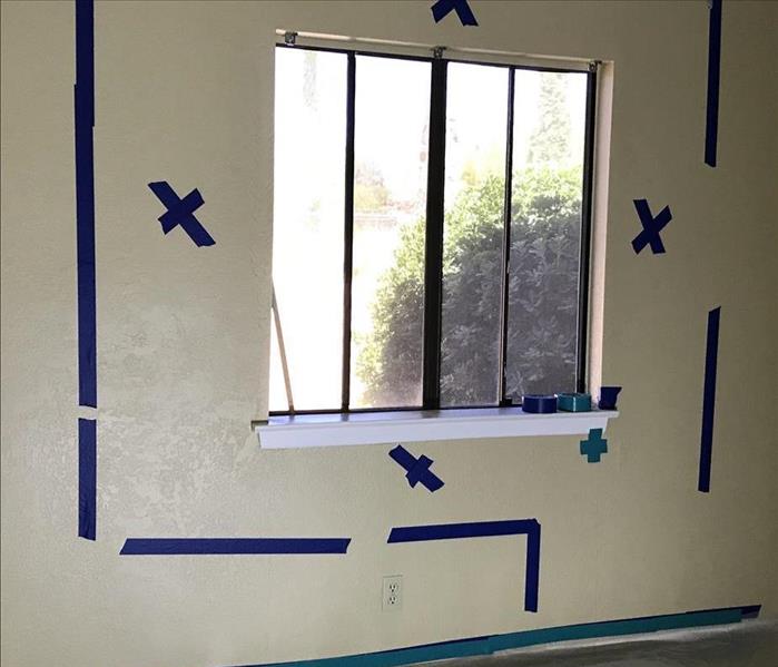 White wall marked with blue x's for drywall removal