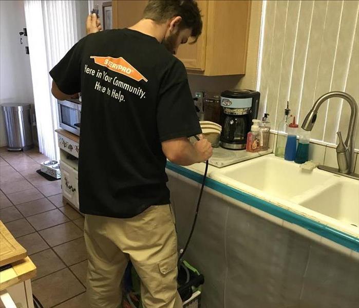 A SERVPRO technician setting up a dehumidifier for a sink leak